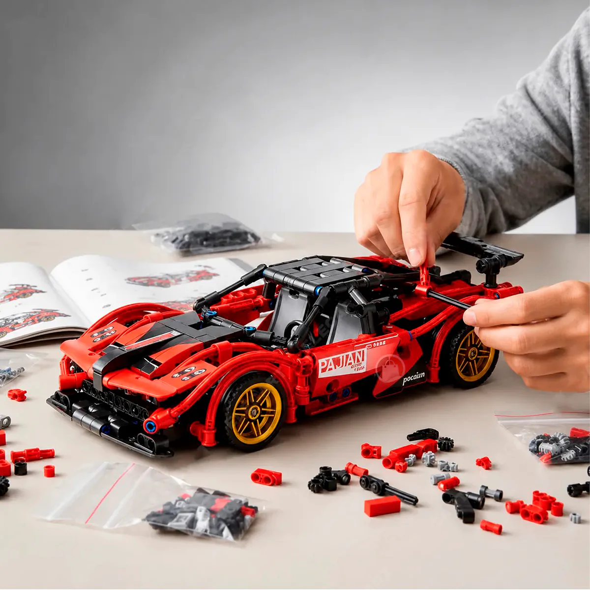 Persona armando el carro de bloques rojo con el manual y las piezas sobre la mesa