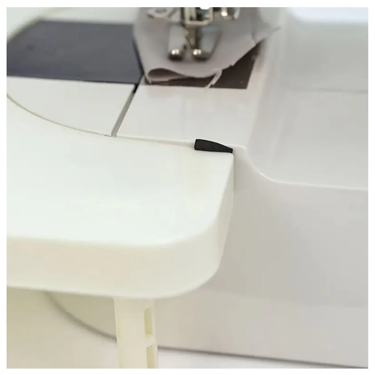 Unión de la mesa de extensión con la mini máquina de coser, con tela bajo el prensatelas