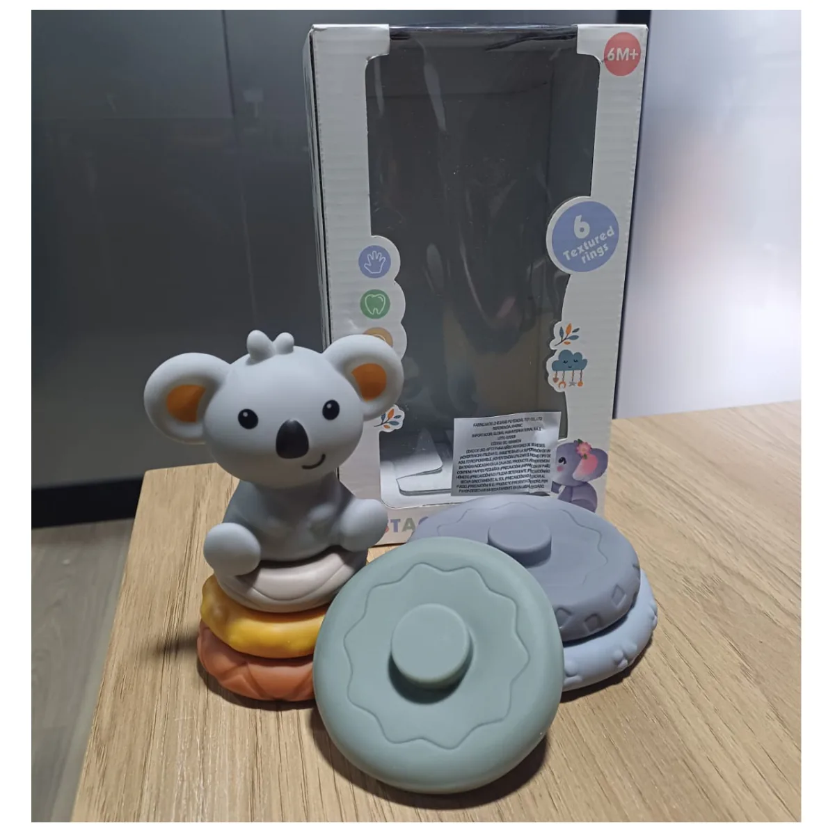Aros apilables y koala junto a su caja, marcada desde 6 meses