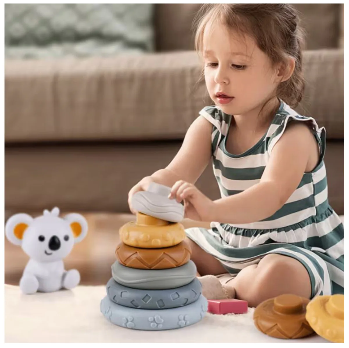 Niña apilando los aros de silicona junto al koala
