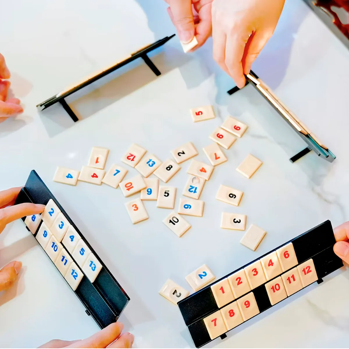 Cuatro personas jugando rummy de viaje sobre una mesa