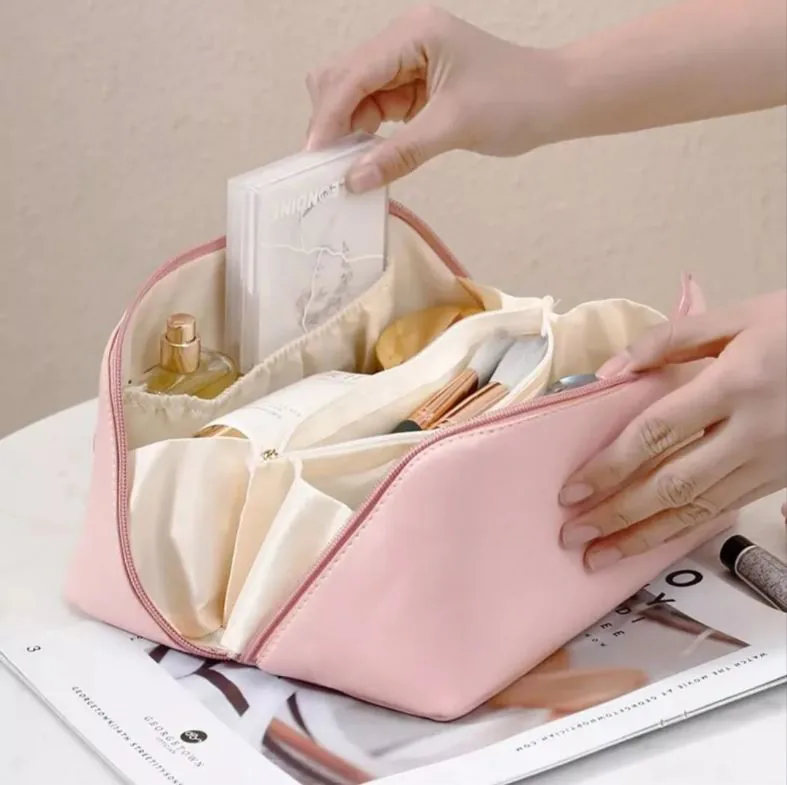 Cosmetiquera rosa abierta con compartimentos llenos de maquillaje