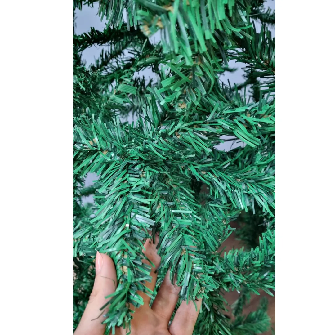 Mano abriendo las puntas verdes del árbol de Navidad artificial