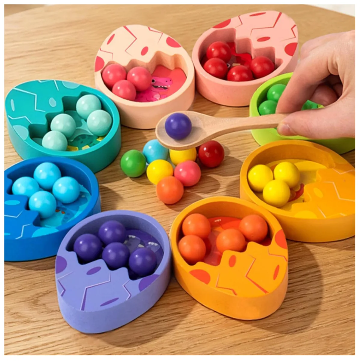 Huevos de dinosaurio de colores con bolitas y una cuchara de madera pasando una bolita